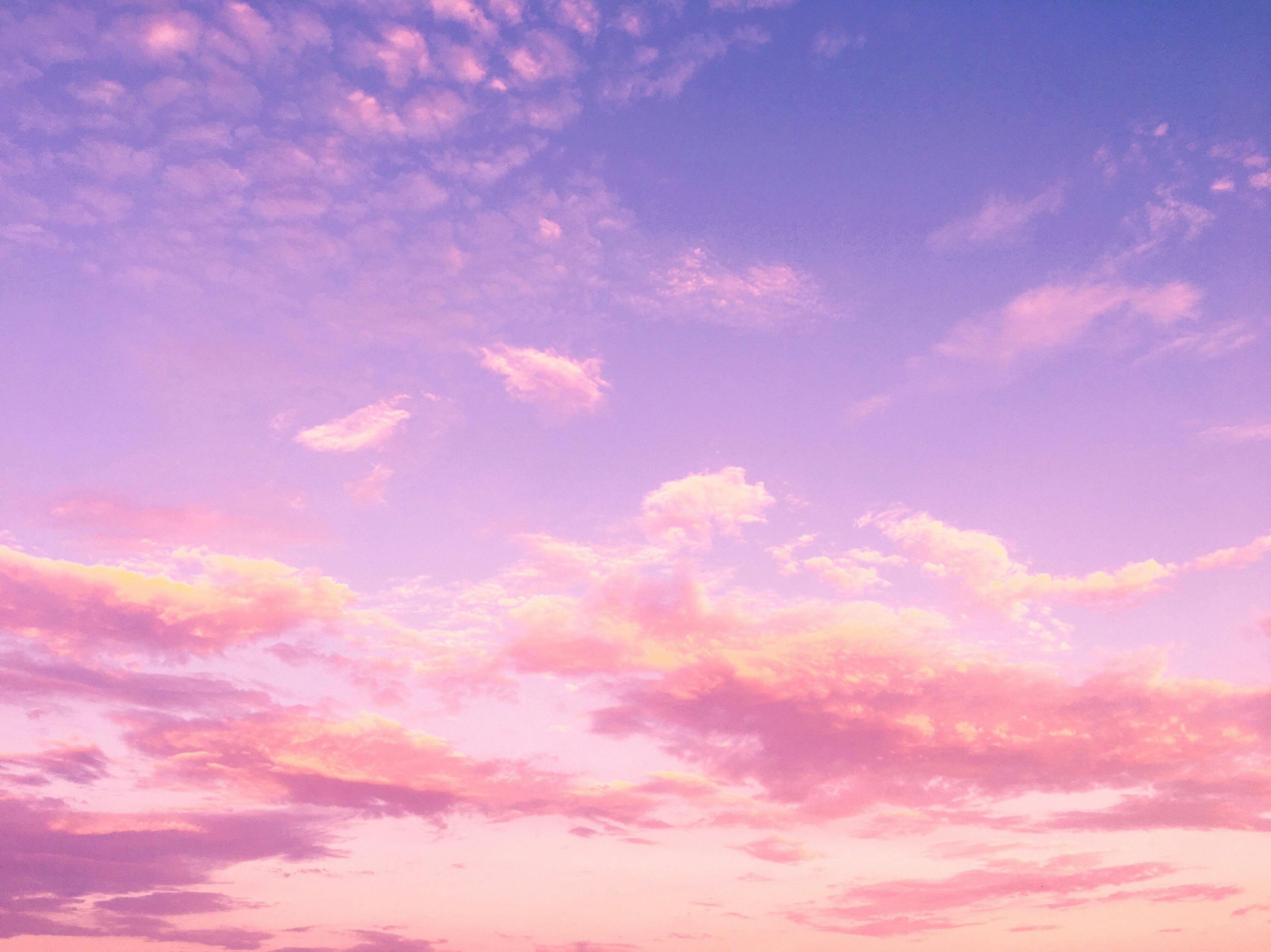 Pastel pink and purple clouds in a clear blue sky
